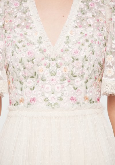 Rochie albă cu broderie florală, decolteu adânc în V, mâneci scurte din dantelă și fustă moale, stratificată din tul decorată cu buline mici.