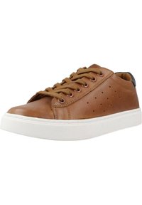 Zapatilla de cuero marrón con detalles laterales perforados, puntera redonda, suela de goma blanca y cordones marrones. Acentuada con una pestaña en el talón de color oscuro.