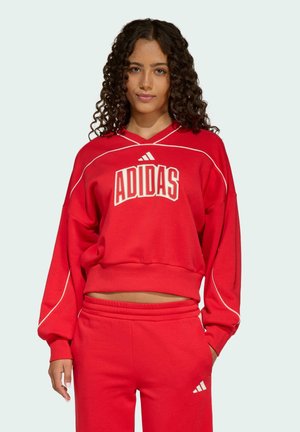 Rode Adidas sweatshirt met witte piping, een ronde halslijn en een gedurfde "ADIDAS" grafiek. Gecombineerd met bijpassende rode sweatpants.