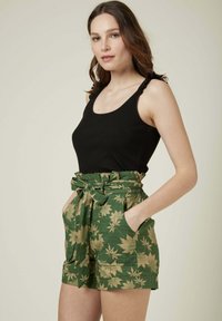 Débardeur noir côtelé avec un short vert présentant un motif de feuille dorée, des détails de ceinture et des poches latérales. Tissu doux et coupe décontractée.