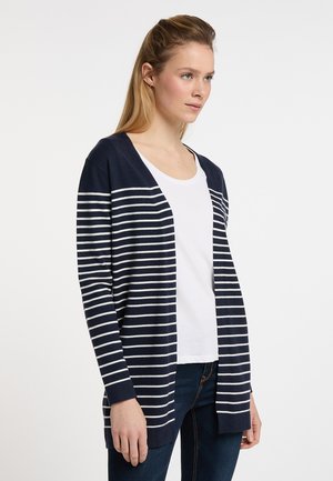 Cardigan a righe blu e bianche con apertura frontale, maniche lunghe e vestibilità morbida; indossato sopra una maglietta bianca e jeans blu.