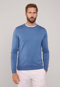 Pull bleu à manches longues en texture douce avec un col rond et des poignets côtelés. Présente un col intérieur blanc contrastant.