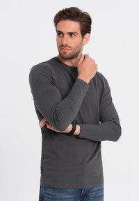 Grijze lange mouw shirt gemaakt van een gladde stof, met een ronde hals ontwerp. De pasvorm is dicht op het lichaam, met een label aan de onderzoom.
