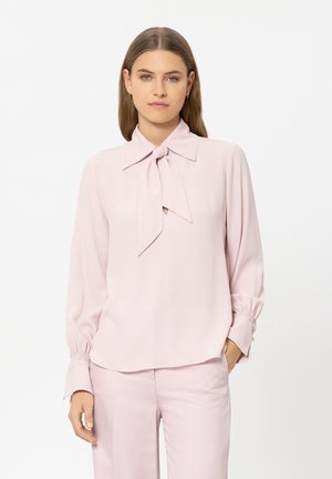 Light pink blouse with a bow tie collar, long sleeves with gathered cuffs, smooth fabric, and a clean silhouette.