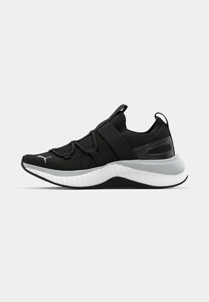 Schwarzer Sportschuh mit strukturiertem Obermaterial, elastischen Riemen und einer dicken weißen Mittelsohle. Mit einem grauen Akzent entlang der Sohle.