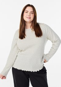 Langärmliges, geripptes Oberteil in Creme mit schwarzen wellenförmigen Streifen. Verfügt über einen runden Halsausschnitt und einen gerafften Saum, kombiniert mit schwarzen Hosen.