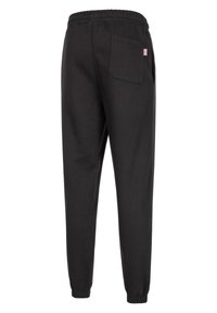Black sweatpants made of cotton, featuring an elastic waistband, cuffed ankles, and a back pocket with a small flag emblem.