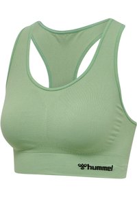 Jasnozielony bezszwowy sportowy biustonosz z konstrukcją racerback i czarnym logo hummel na elastycznym pasku spodnim.