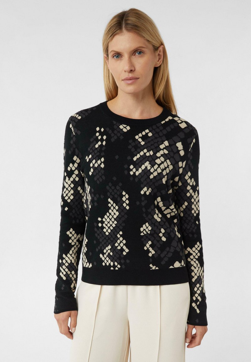 Schwarzer und cremefarbener Pullover mit geometrischem Muster, Langarm, Rundhalsausschnitt, aus weichem Strickmaterial gefertigt.