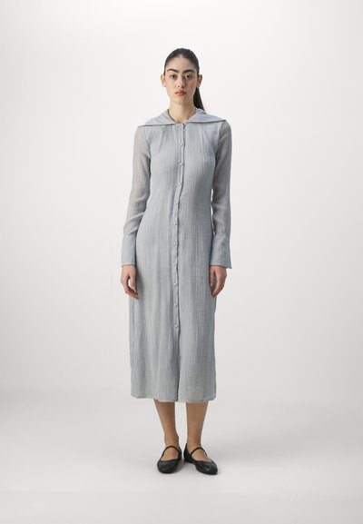Gray, long-sleeve dress with a button front, a collar, and textured fabric. Worn with black shoes, features a mid-calf length and relaxed fit.