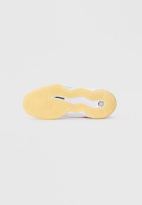 Suela de zapato con una base de goma amarilla que presenta patrones de banda de rodadura circulares, un entresuela blanca y una textura de superficie lisa y flexible.