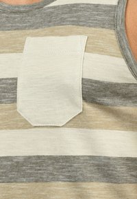 Camiseta sin mangas a rayas con rayas estrechas en beige, gris y blanco roto, con un bolsillo rectangular en el pecho y una textura de tela suave.