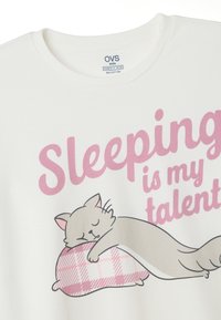 Weißes T-Shirt aus Bio-Baumwolle, mit einer Illustration einer schlafenden Katze und pinkem Text: "Schlafen ist mein Talent." Weicher Stoff.