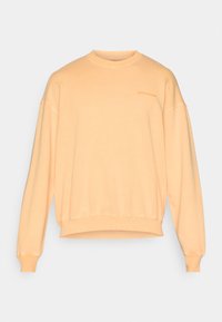 Felpa color pesco realizzata in cotone morbido. Presenta un collo rotondo, spalle scese, polsini a coste e un piccolo logo sul petto.
