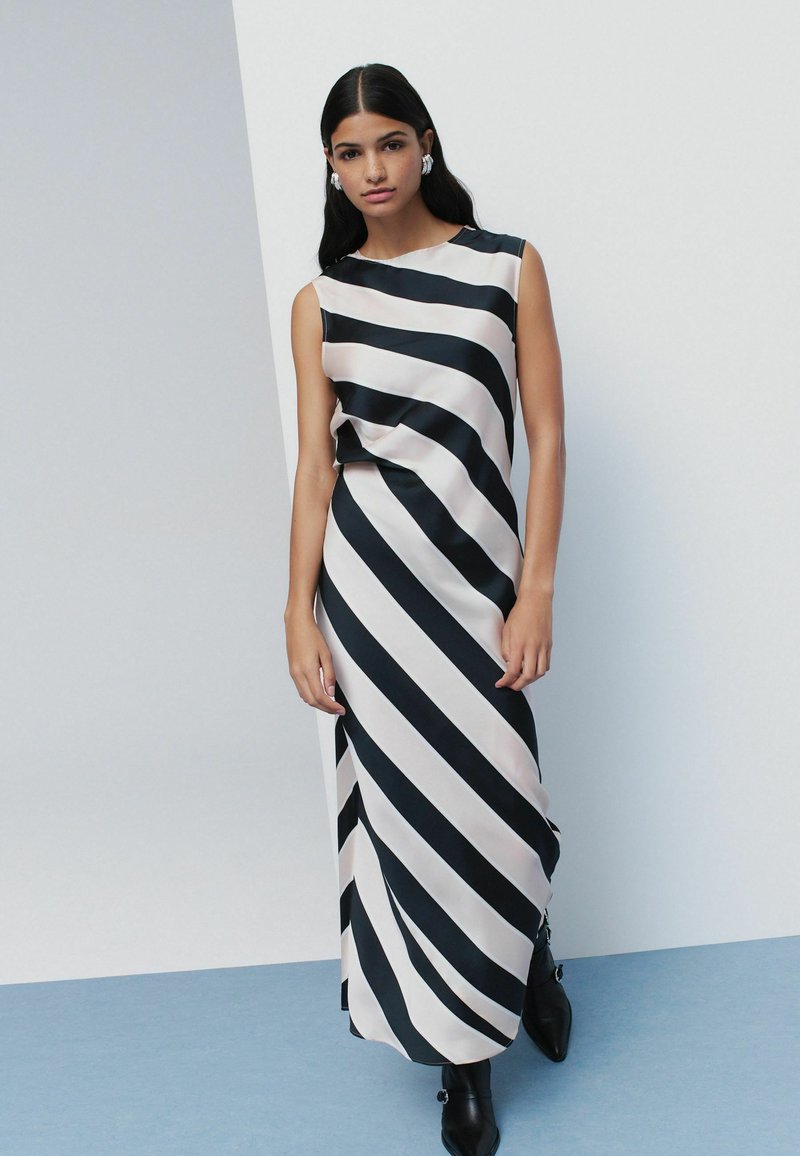 Vestido maxi sin mangas con rayas diagonales en negro y rosa pálido, hecho de una tela suave, con escote redondo y corte holgado.