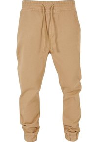 Beige katoenen jogpants met een elastische tailleband, een trekkoord en elastische boorden, met een gladde textuur en een taps toelopend ontwerp.