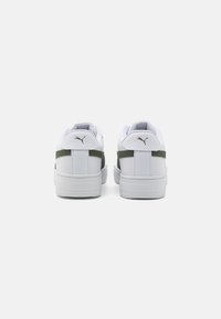Valged tennised tekstureeritud nahast ülemise osaga, rohelised kangast aktsendid kontsapadjale ja valge kummist tald. PUMA logo taga.