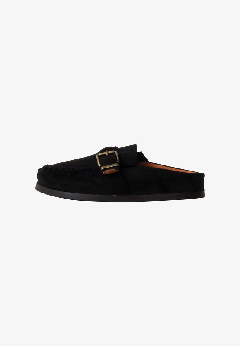 Mocassin en daim noir à enfiler avec boucle latérale et semelle basse en caoutchouc, vu de l’intérieur sur fond blanc.