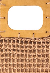 Pleciony kosz w jasnobeżowym materiale z prostokątnym drewnianym uchwytem i otwartym wzorem plecionki. Posiada widoczne szwy, które dodają struktury.