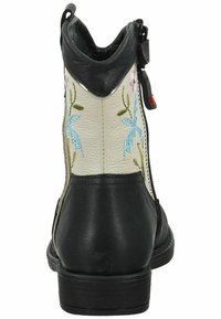 Bottine en cuir noir avec panneau en cuir blanc. Elle présente une broderie florale en bleu et rose. Fermeture éclair sur le côté et un petit talon carré.