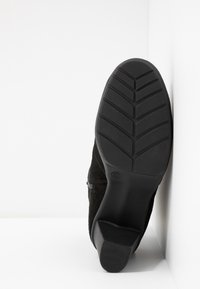 Czarny zamszowy botek za kostkę z gumową podeszwą, zdobiony teksturowanym wzorem chevron. Rozmiar 37 oznaczony na podeszwie. Prosty, elegancki design.
