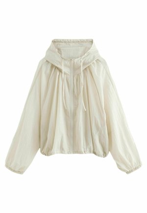 Veste légère beige clair à capuche, fermeture éclair intégrale sur le devant, cordons de serrage, poignets et ourlet élastiques, présentée sur fond blanc.