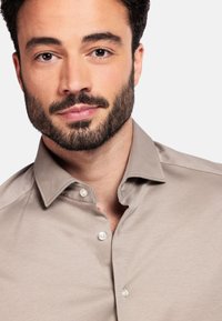 Lichtbruin overhemd met korte mouwen, voorzien van een klassieke kraag en knopen, gemaakt van een gladde stof. Gestructureerde afwerking met een op maat gemaakte pasvorm.