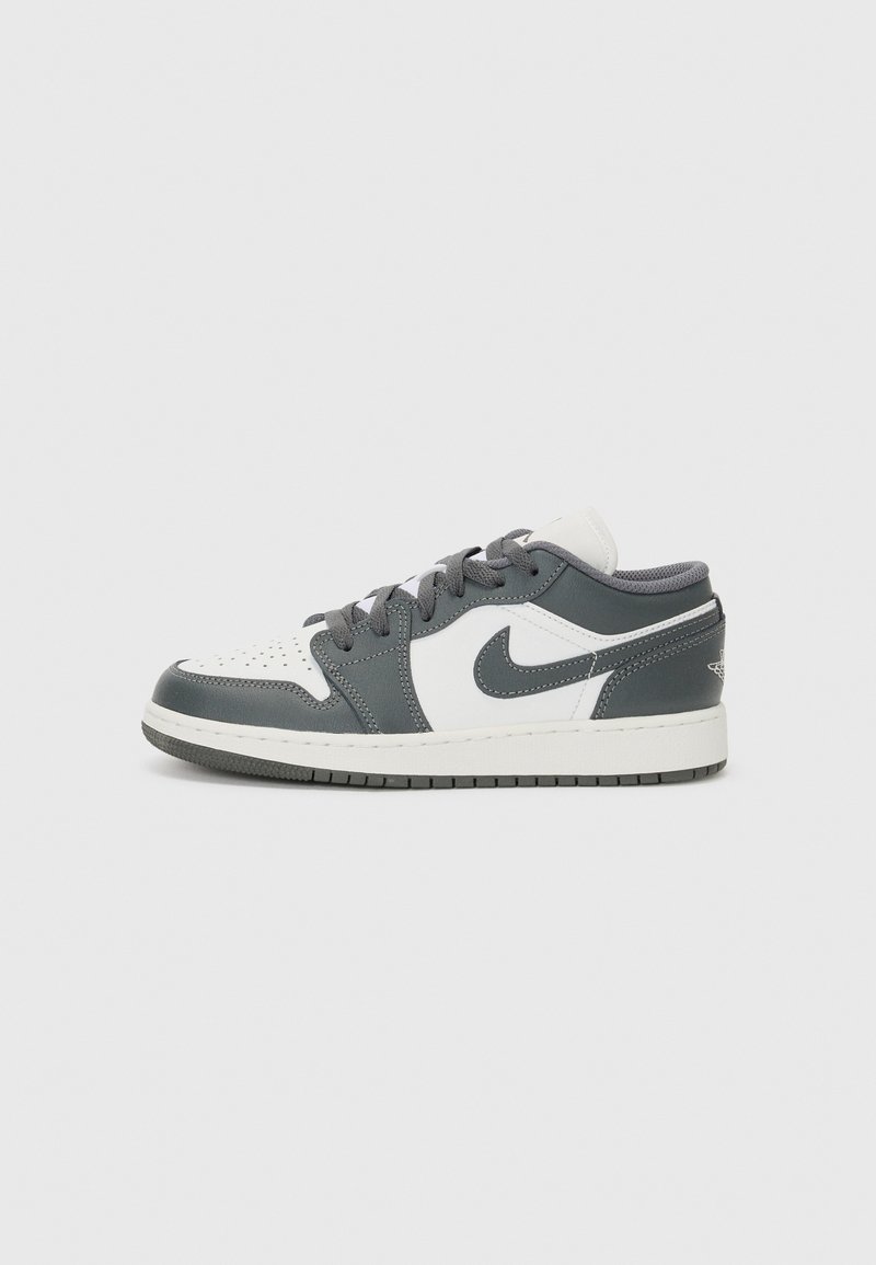 Baskets basses avec une tige principalement grise, un Swoosh blanc en contraste, une pointe perforée, des lacets gris et une semelle en caoutchouc texturée.