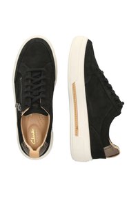 Schwarze Wildleder-Sneaker mit weißen Gummisohlen, ausgestattet mit einem seitlichen Reißverschluss, runden Schnürsenkeln und einem braunen Lederelement an der Ferse.