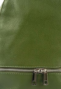 Groene leren tas met een gestructureerd oppervlak, gebogen vorm en een zilveren ritsluiting met dubbele trekker. Gladde afwerking, eenvoudig ontwerp.