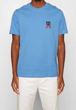 Blå bomulds T-shirt med rund halsudskæring og korte ærmer. Har et lille multicolor logo på venstre bryst. Glat tekstur.