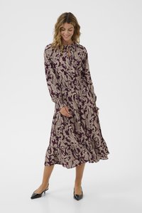 Langes kastanienbraunes Kleid mit beigem Blumenmuster, gerafftem Ausschnitt und elastischem Bund. Verfügt über lange Ärmel und einen ausgestellten Saum. Getragen mit schwarzen Absätzen.