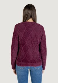 Maglione bordeaux peloso con motivo a rombi, maniche lunghe e scollatura rotonda. Texture morbida, vestibilità rilassata e orlo a coste.