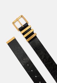 Juodas odinis diržas turi struktūrizuotą paviršių ir aukso spalvos metalinį sagtį su paralelinėmis akcentų juostelėmis. Prekės ženklas "Michael Kors" išgraviruotas ant sagties.