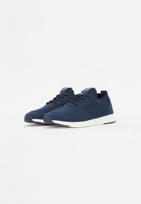 Navy blue athletic shoes with mesh upper, textured side accents, lace-up design, and white rubber sole for traction and comfort.