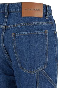 Jeans aus Denim in einem dunklen Blauton. Mit einem Lederpatch an der Taille, auf dem "2Y STUDIOS" geprägt ist. Sichtbare Nähte und Details der Taschen.