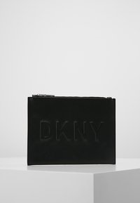 Pochette DKNY en cuir noir avec logo embossé à l'avant, fermeture éclair, texture lisse et forme rectangulaire.