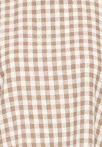 Tissu à carreaux vichy beige et blanc avec une apparence légèrement texturée et tissée.