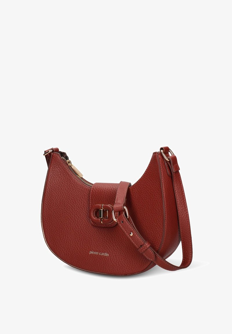 Borsa in pelle rossa con texture, forma curva, chiusura con zip e dettaglio con fibbia. Dotata di tracolla regolabile. Nome del marchio stampato sul davanti.