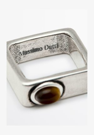 Bague en métal carré avec une finition argentée brossée. Présente un accent en pierre brune ronde d'un côté et une marque gravée à l'intérieur.