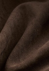 Hnedá látka s jemným, textúrovaným povrchom, zobrazujúca jemné variácie v farbe a vzore, prehodená v jemných záhyboch.