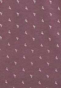 Tkanina tekstylna w głębokim mauve z małymi białymi wzorami liści. Tekstura jest żebrowana, co zapewnia dotykowe odczucie i wizualne zainteresowanie.