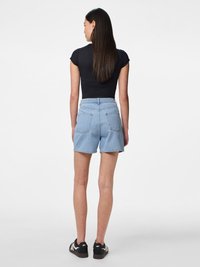 Džínové šortky v světle modré barvě s vysokým pasem, zadními kapsami a volným střihem. Nosené s černým upnutým topem a černými teniskami.