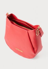 Bolsa de mão em sintético vermelho com um design geométrico, ferragens douradas e dois compartimentos com fecho zip. Apresenta o logótipo "LOVE MOSCHINO" na parte da frente.