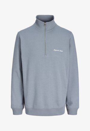 Maglione azzurro chiaro a maniche lunghe con mezza cerniera e collo alto, con una piccola scritta bianca "Originals Studio" sul lato sinistro del petto.