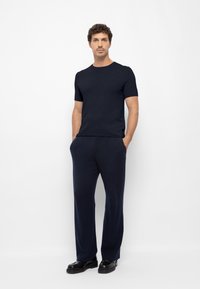 Navyblauwe t-shirt met korte mouwen, gecombineerd met bijpassende wijde broek, beide in een zachte, soepele stof. Zwarte schoenen maken de outfit compleet.