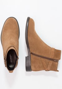 Bruna mockaskor med ankellängd, sidodragkedja, fyrkantig tå, låg klack och subtila sömnadsdetaljer. Släta läderfoder inuti.