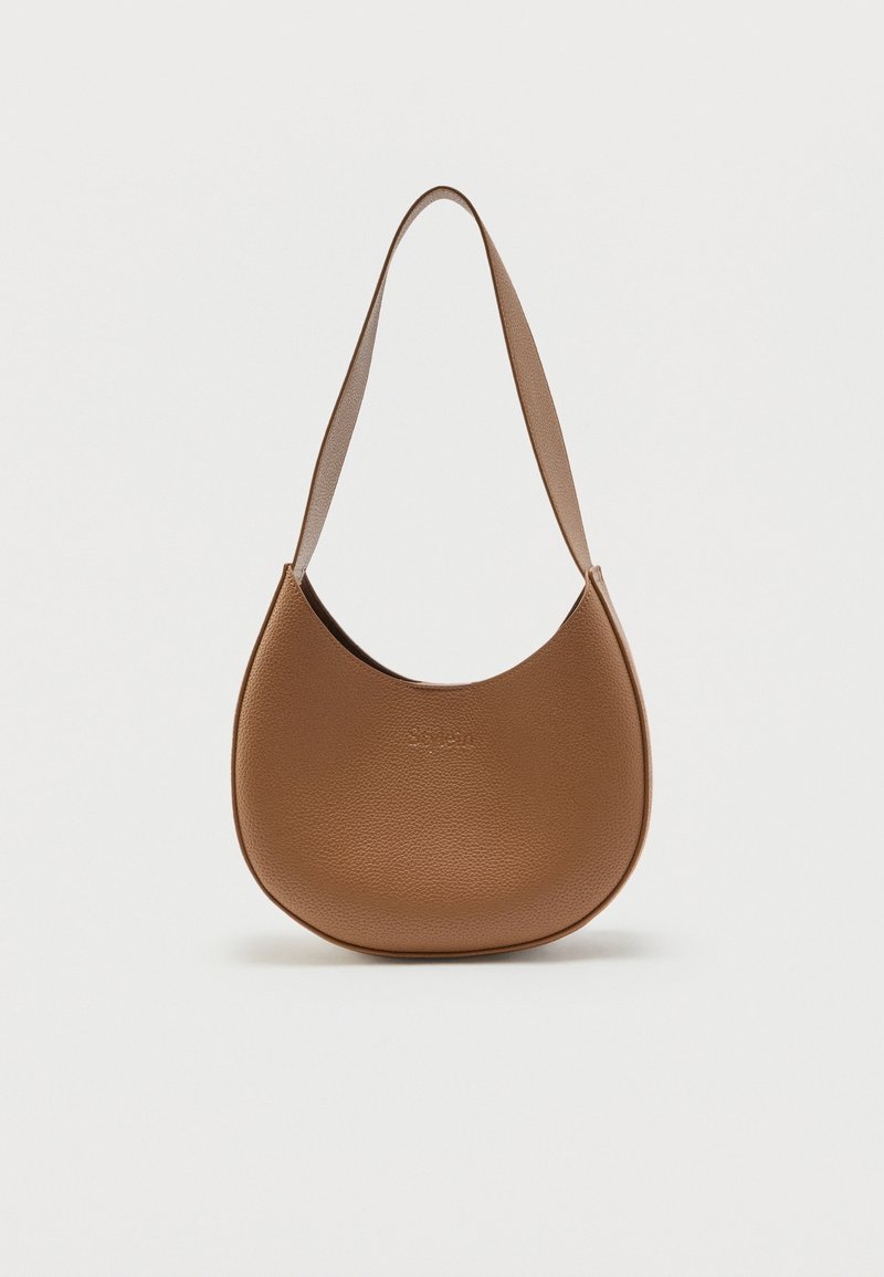 Καφέ δερμάτινη τσάντα ώμου σε σχήμα ημισελήνου με φαρδιά λουρίδα και υφή από μικρές κόκκους, εμφανίζεται σε απλό ανοιχτόφωτο φόντο.