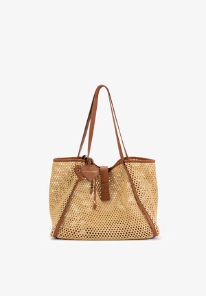 Bolso tote de paja tejida con detalles de cuero marrón, dos asas largas y una pequeña etiqueta de cuero colgando cerca de la parte superior central.