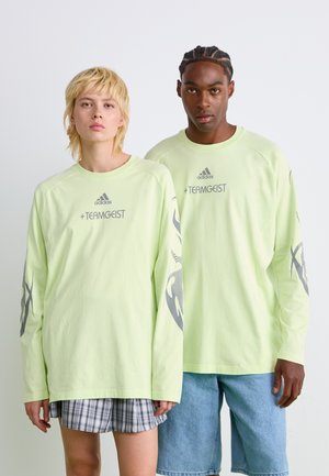 Langärmliges, hellgrünes Shirt mit grauen Grafiken. Verfügt über einen runden Halsausschnitt und eine lockere Passform. Das Material scheint weich zu sein und eignet sich gut für Freizeitkleidung.